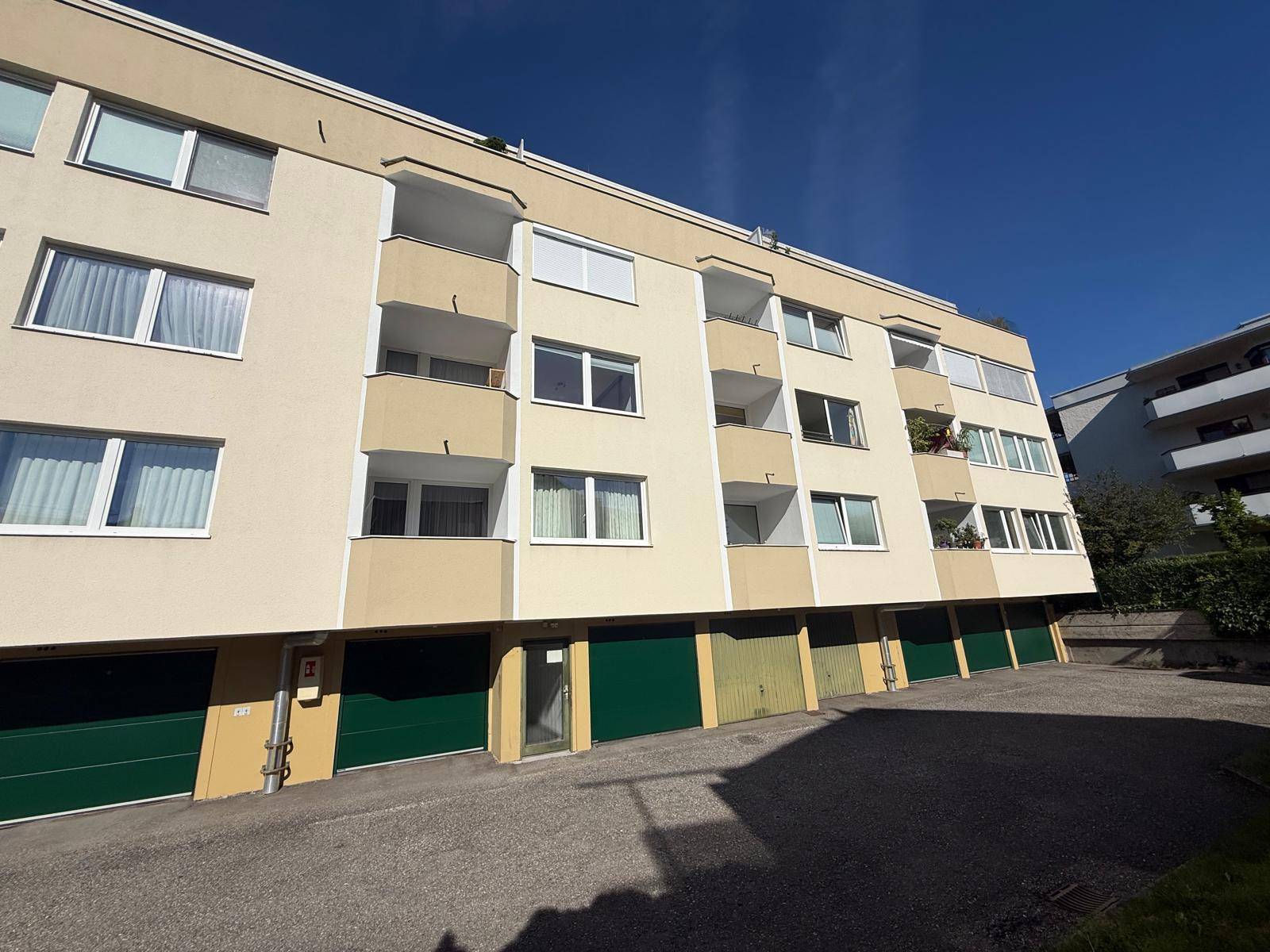 Mehrfamilienhaus mit mehreren Balkonen und Garagen im Erdgeschoss.