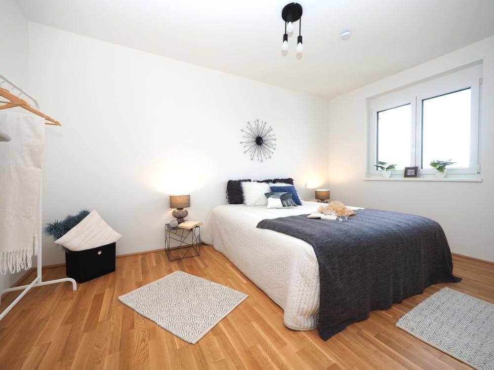 Gemütliches Schlafzimmer mit Doppelbett, Holzboden und großem Fenster für viel Licht.