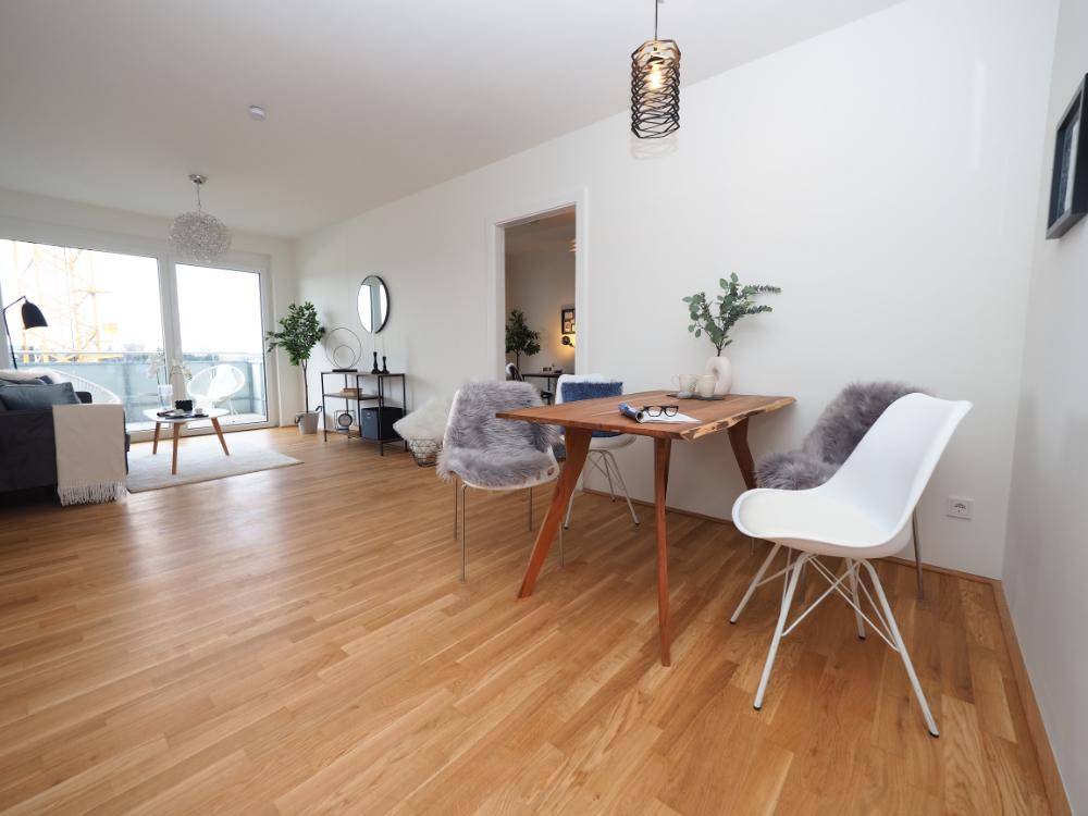 Geräumiger Wohn-Essbereich mit Holzboden, modernem Esstisch und hellem Ambiente.