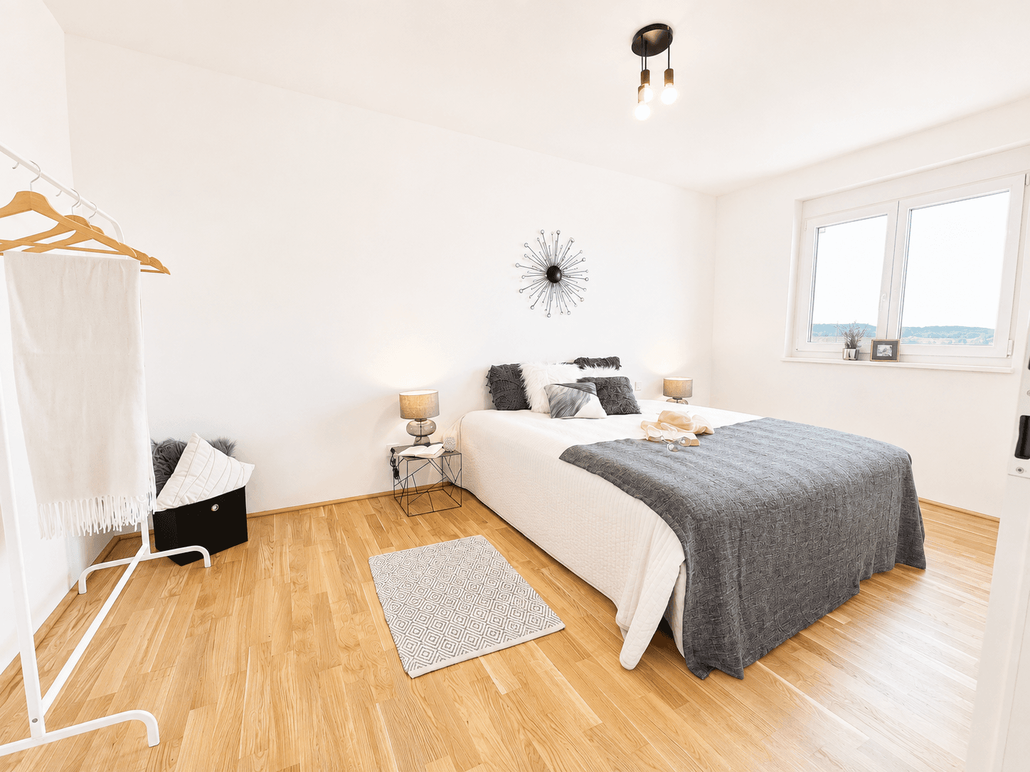 Helles Schlafzimmer mit Holzboden, Doppelbett und Fenster mit Blick ins Grüne.