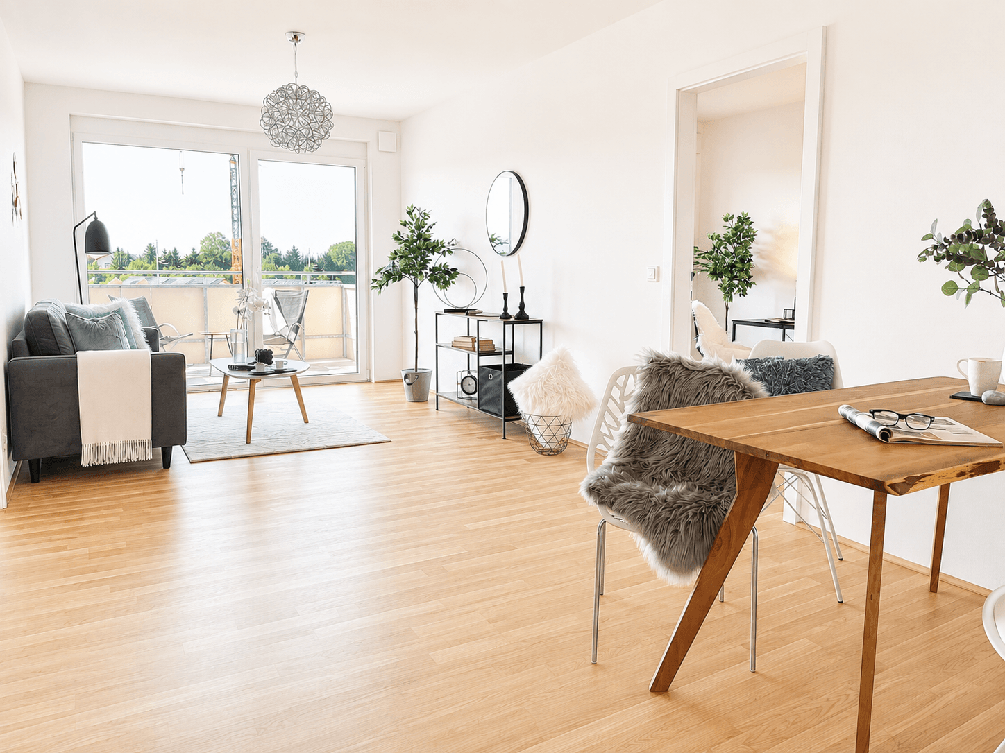 Helles Wohn-Esszimmer mit Holzboden, modernem Sofa und Zugang zu einem Balkon.