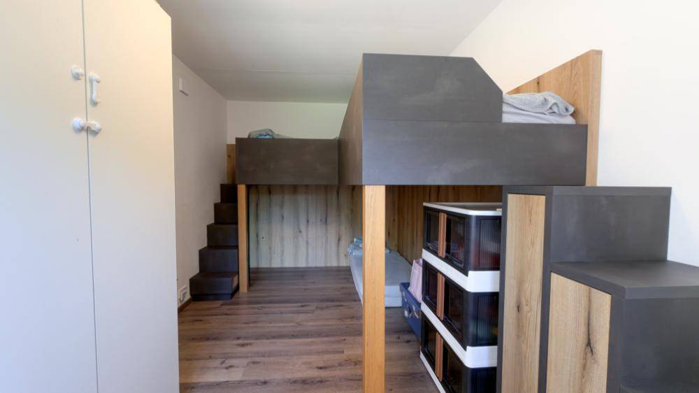 Kinderzimmer mit Hochbettkonstruktion, Stauraum und Holzboden in modernem Design.