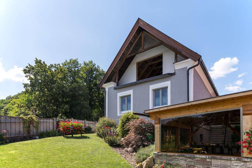 Gepflegter Gartenbereich neben dem Haus mit Rasenfläche und blühenden Sträuchern.