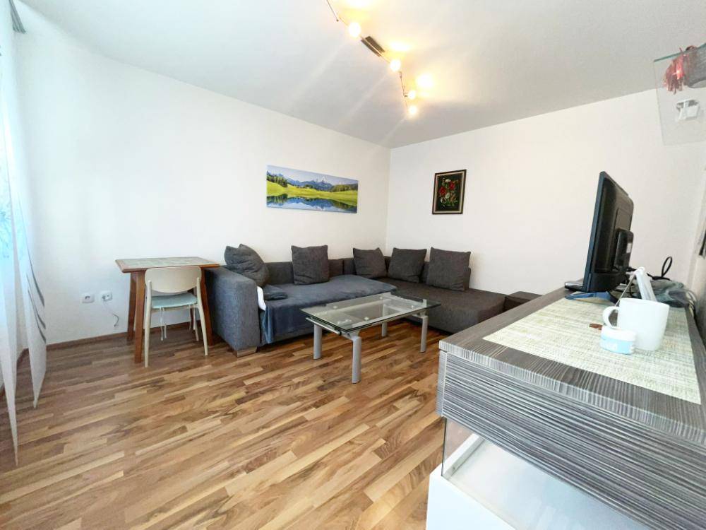 Gemütlicher Wohnbereich mit bequemer Couch, Holzboden und einem kleinen Esstisch für gesellige Momente.