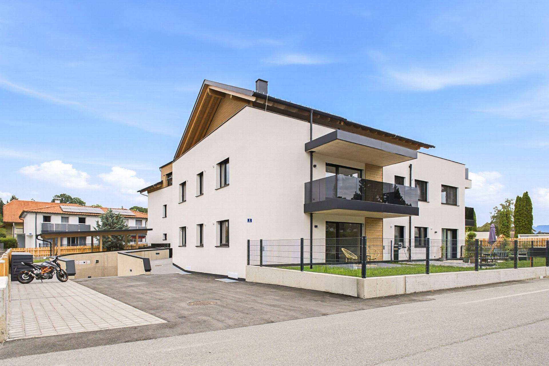 Rückansicht des modernen Wohnhauses mit Balkonen, Parkplätzen und Zugang zur Tiefgarage.