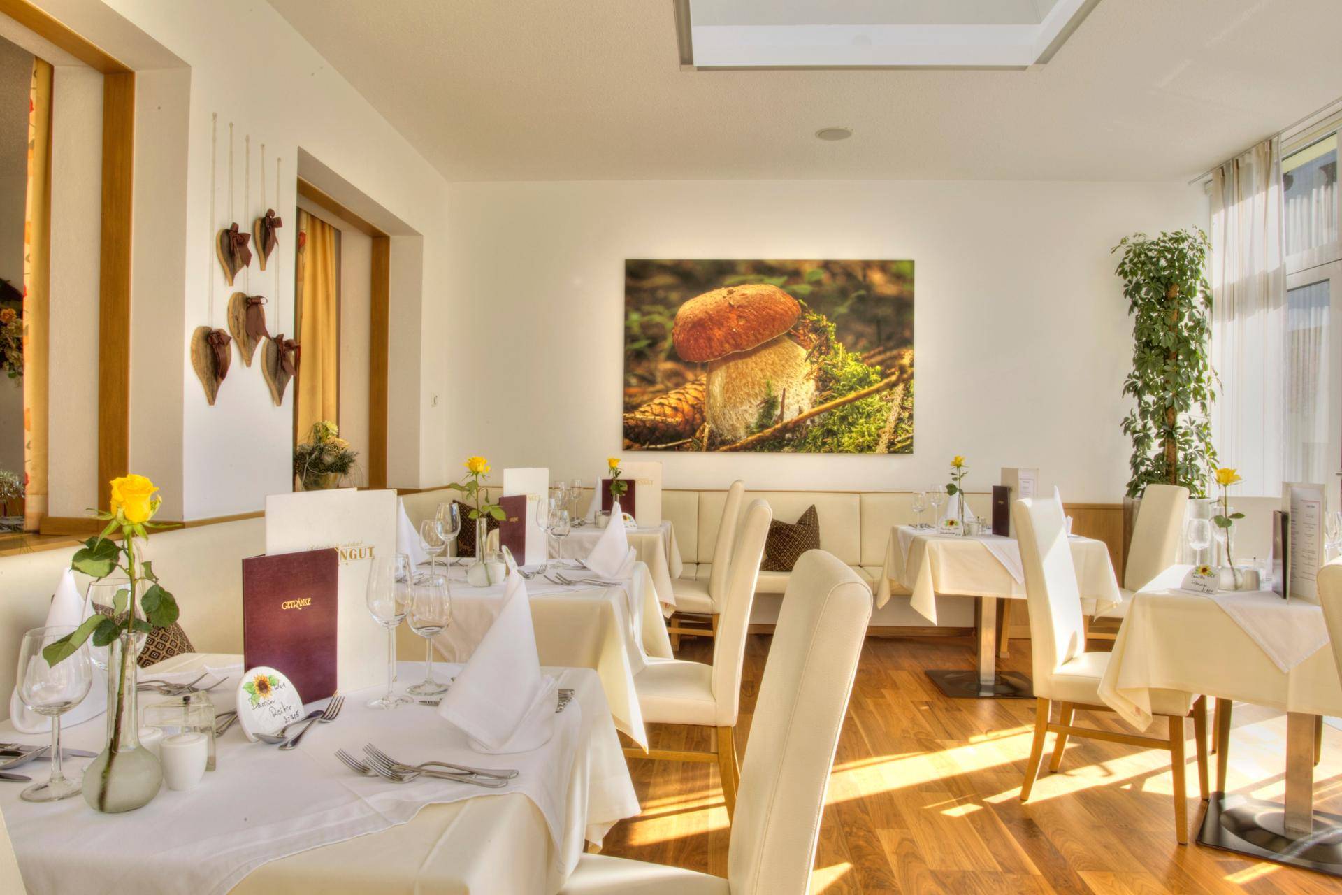 Heller Restaurantbereich mit weiß gedeckten Tischen, eleganten Stühlen und einem großen Wandbild.