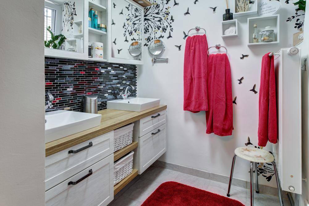 Modernes Badezimmer mit Doppelwaschbecken, Mosaikfliesen und farbenfroher Dekoration.