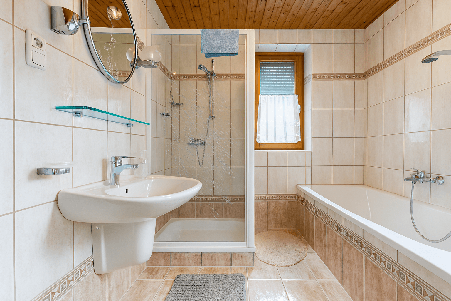 Funktionales Badezimmer mit Badewanne, Duschkabine, Waschbecken und Holzdecke.
