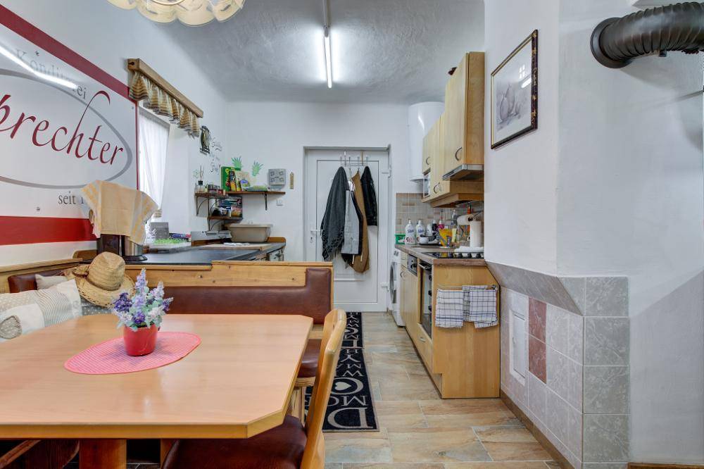 Rustikale Wohnküche mit Holztisch, Eckbank und traditionellem Kachelofen.