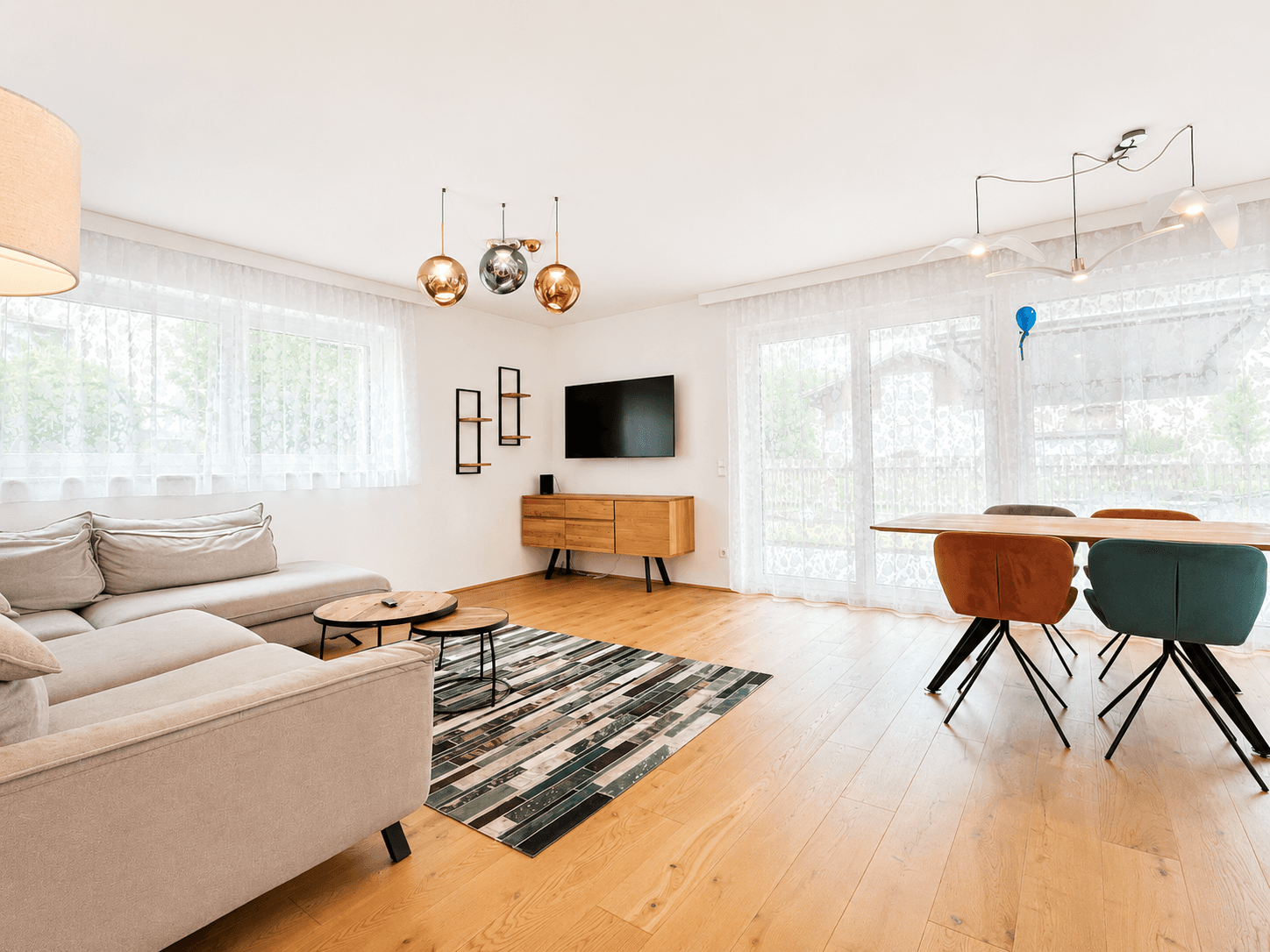 Gemütlicher Wohnbereich mit bequemer Couch, Esstisch und großen Fenstern für viel Tageslicht.