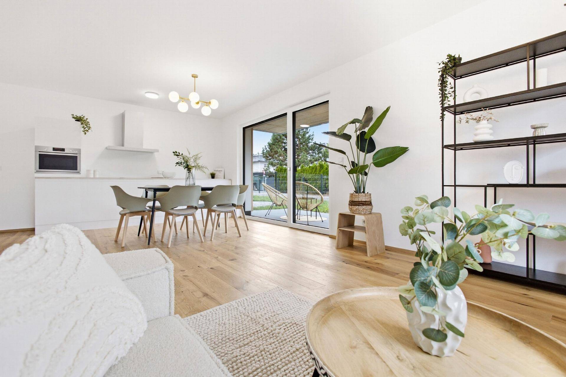 Heller offener Wohn-Essbereich mit moderner Küche, Holzboden und Zugang zum Garten.