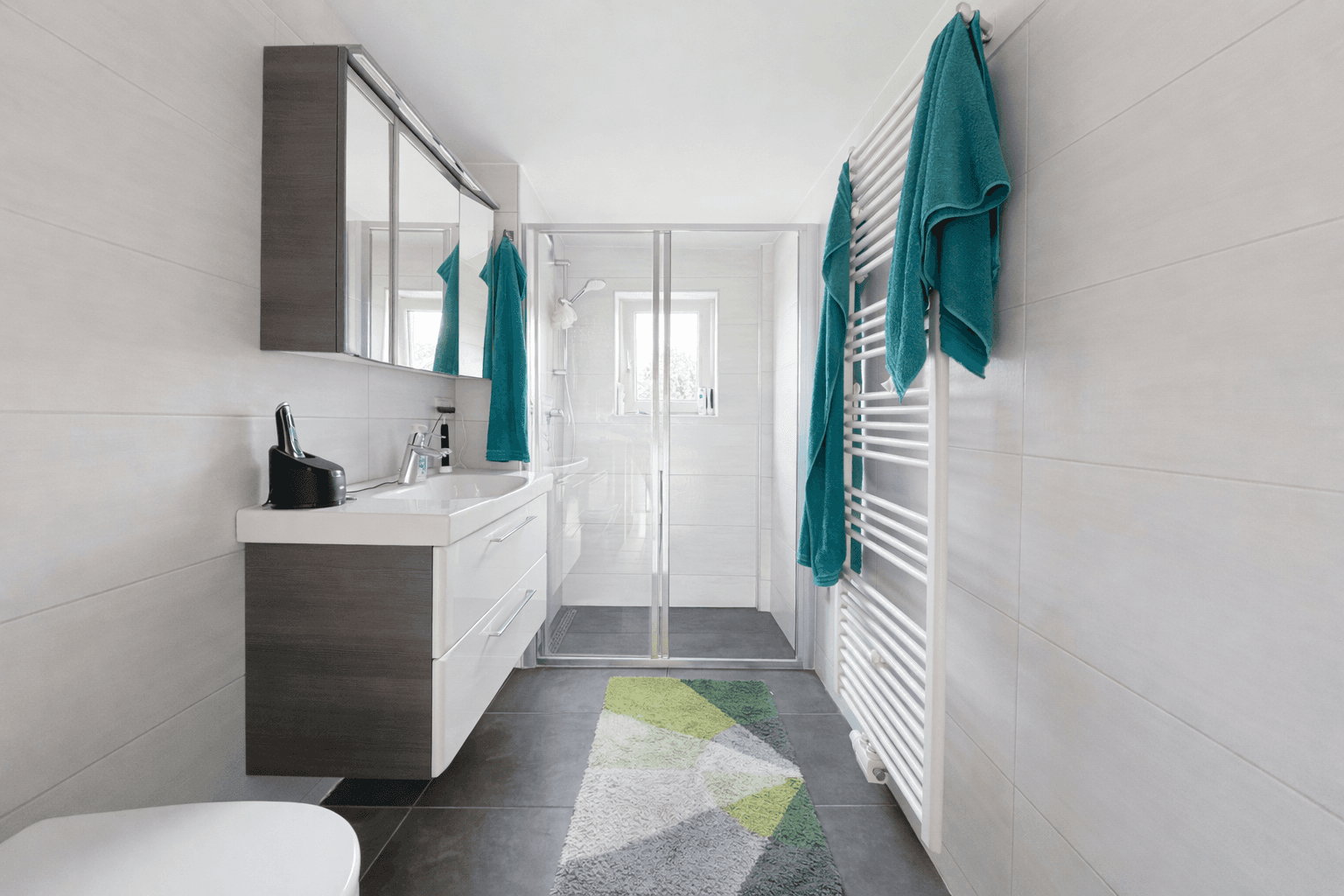 Modernes Badezimmer mit ebenerdiger Dusche, Einzelwaschbecken und beheiztem Handtuchhalter.