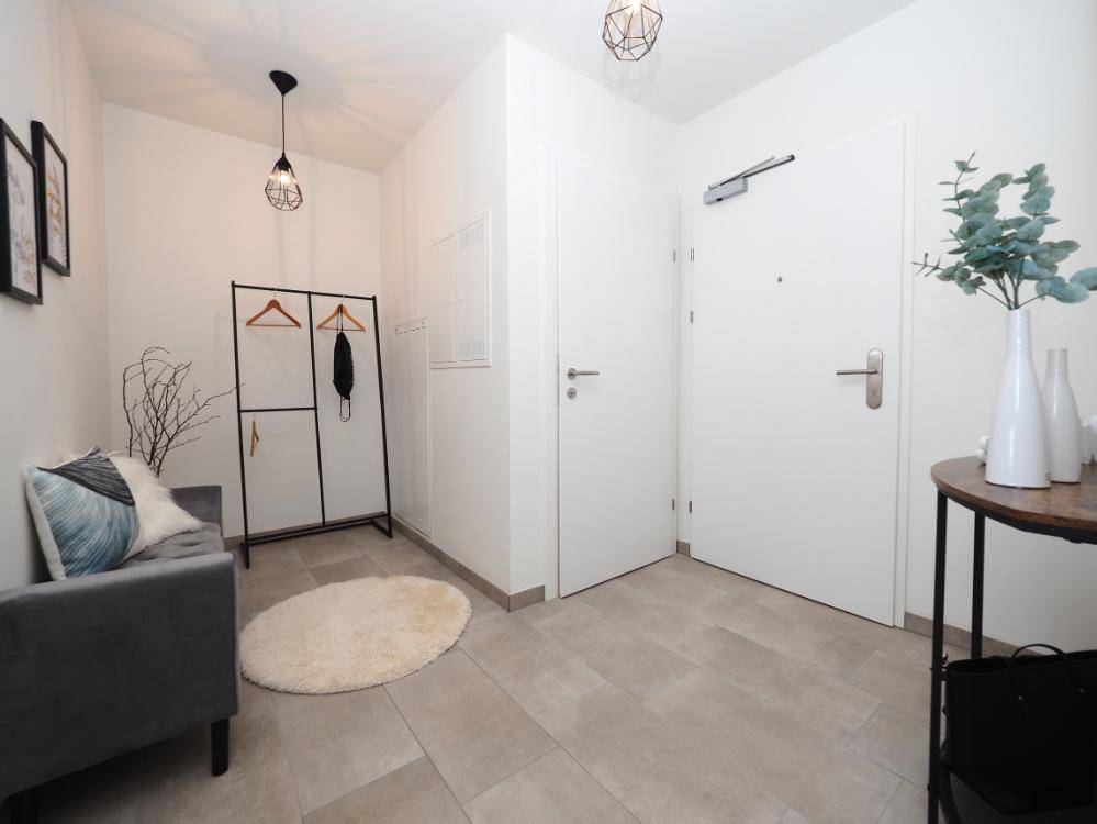 Heller Eingangsbereich mit Fliesenboden, Garderobe und moderner Dekoration.