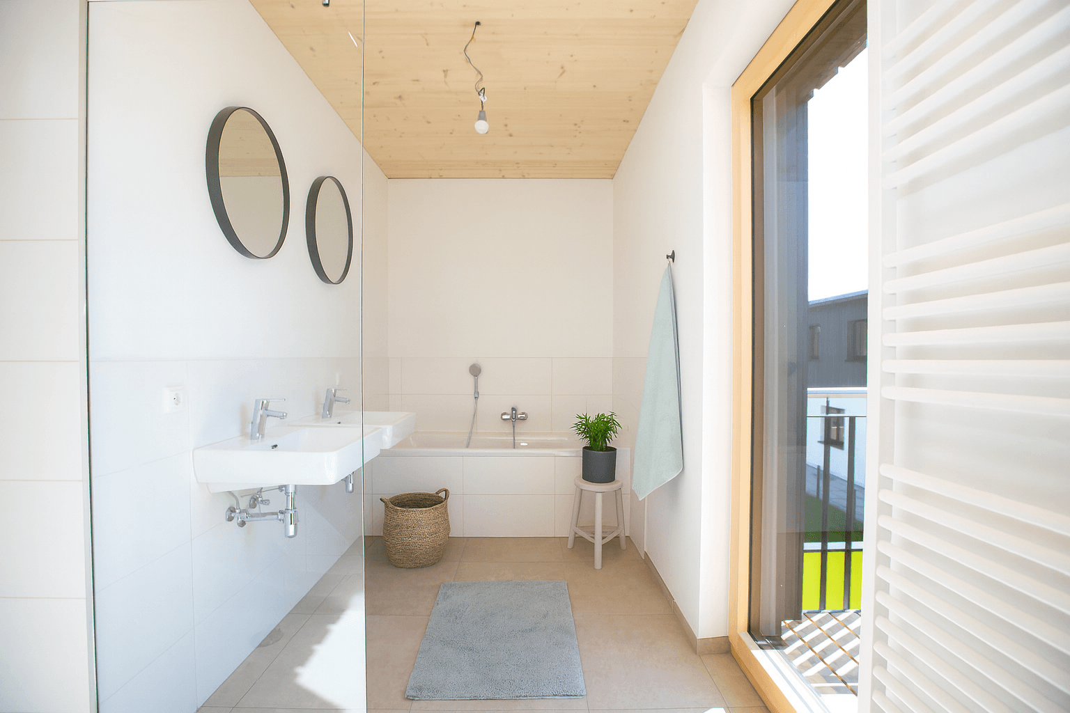 Modernes Badezimmer mit Doppelwaschbecken, Badewanne und Zugang zum Balkon.