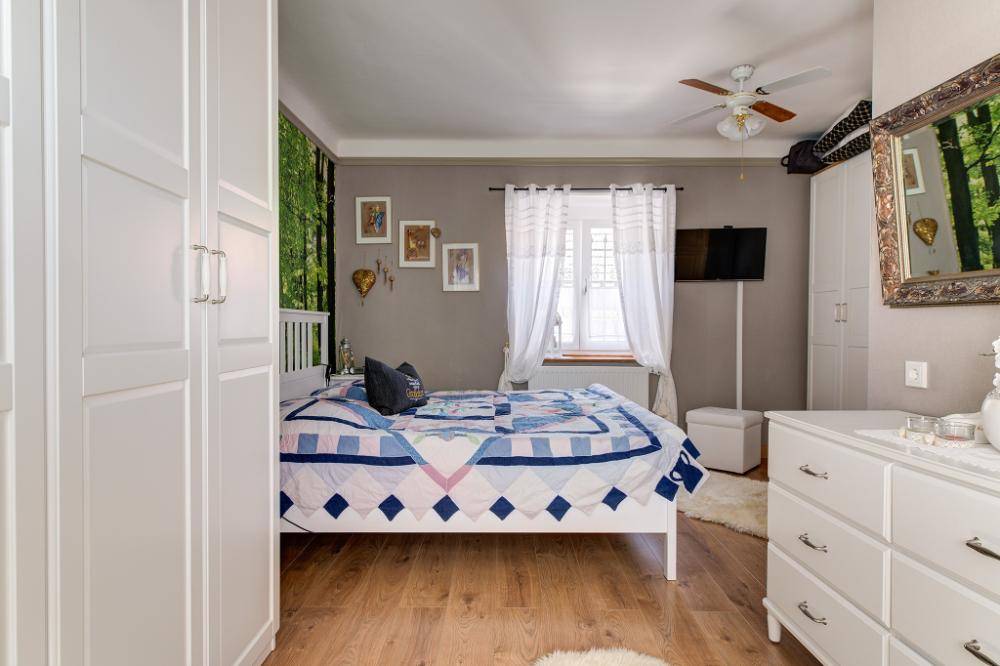 Helles Schlafzimmer mit Holzboden, weißen Schränken und dekorativer Waldtapete.