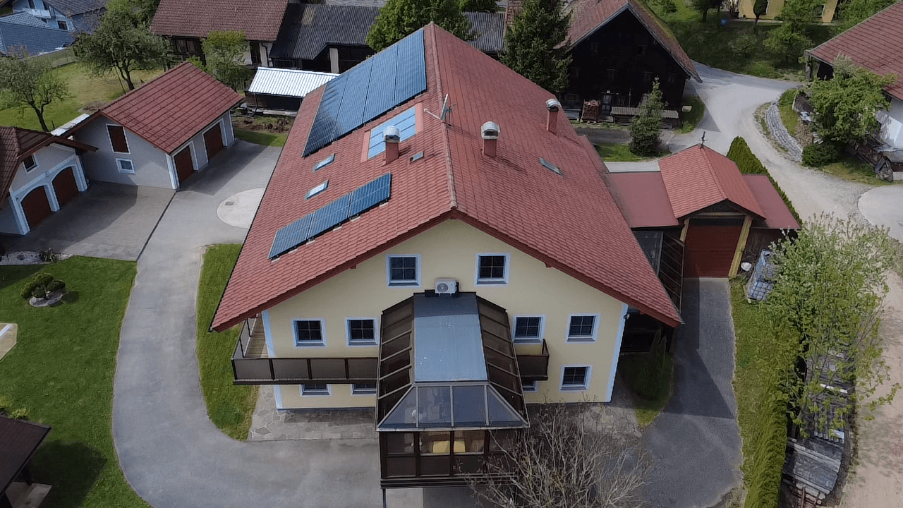 Draufsicht auf das Wohnhaus mit Solarmodulen auf dem Dach und gepflegtem Gartenbereich.