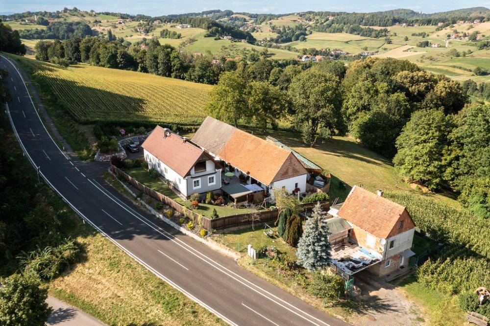 Luftaufnahme eines Anwesens mit mehreren Gebäuden, umgeben von Weinbergen und grüner Landschaft.