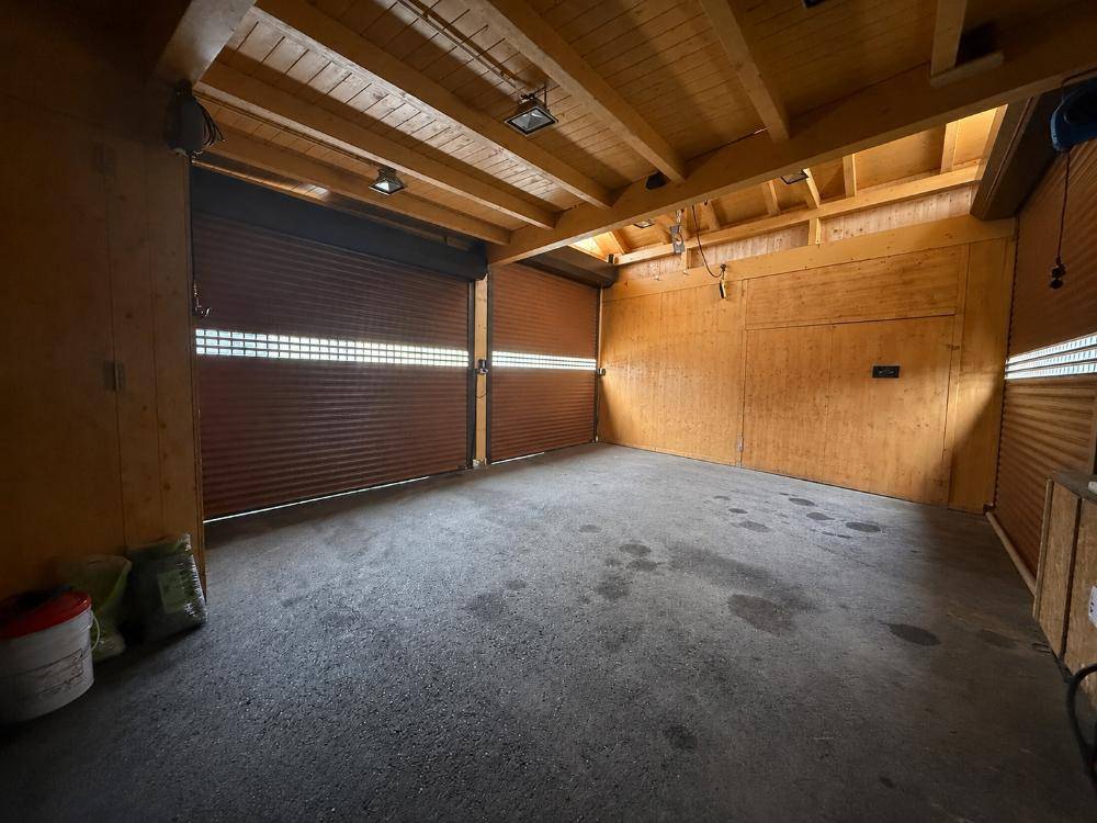 Geräumige Garage mit Holzbalkendecke und zwei Rolltoren.