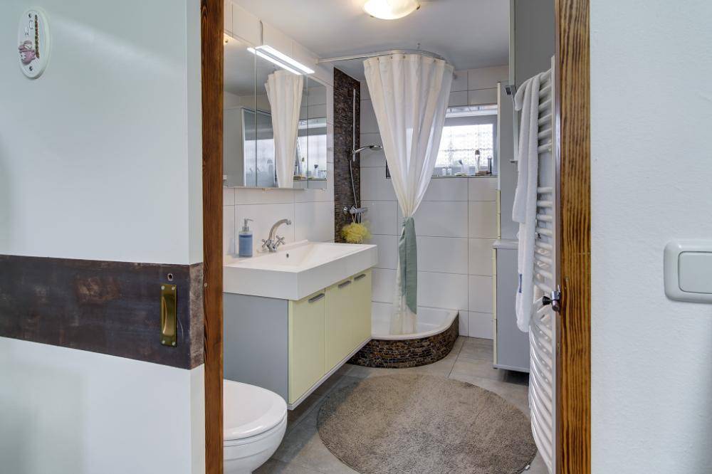 Funktionales Badezimmer mit Dusche, Waschbecken und beheiztem Handtuchhalter.