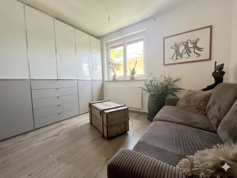 Wohnzimmer mit bequemer Couch, großem Schrank und Fenster für viel Tageslicht.
