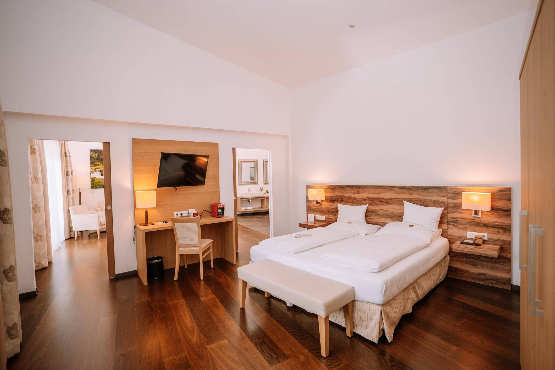 Komfortables Schlafzimmer mit Doppelbett, Schreibtisch und Fernseher, offen zum Wohnbereich.