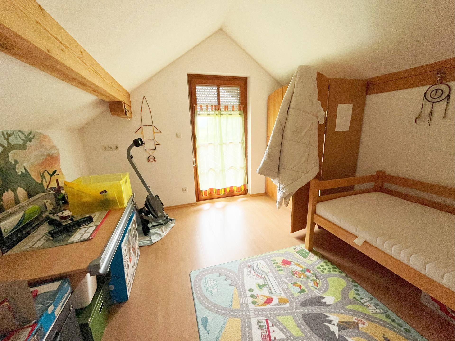 Helles Kinderzimmer mit Holzbett, Schreibtisch und Dachschräge.
