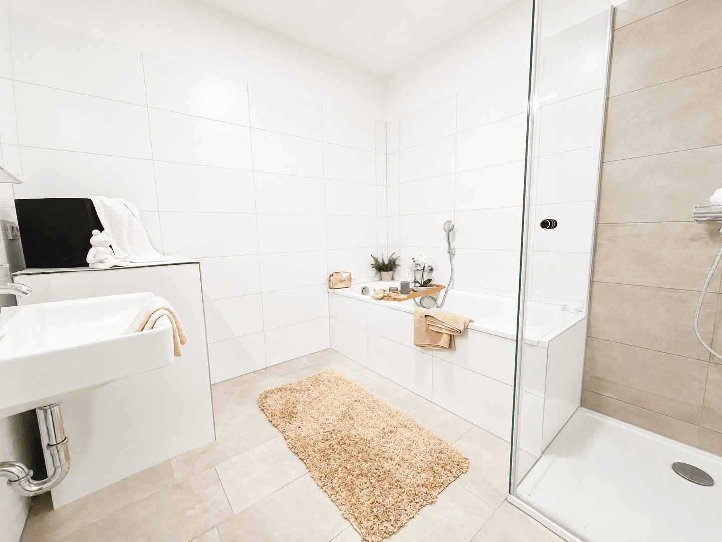 Modernes Badezimmer mit Badewanne, Dusche und weißen Fliesen in heller Atmosphäre.