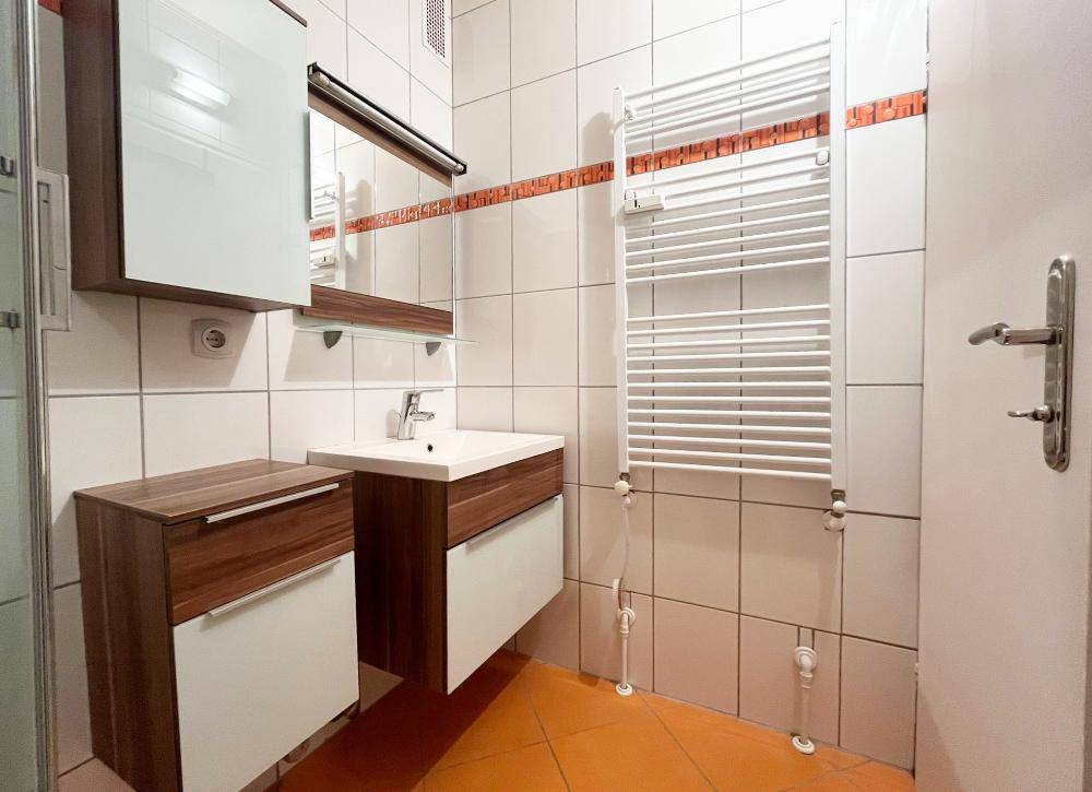 Funktionales Badezimmer mit Waschbecken, Spiegelschrank und beheiztem Handtuchhalter für Komfort und Wärme.