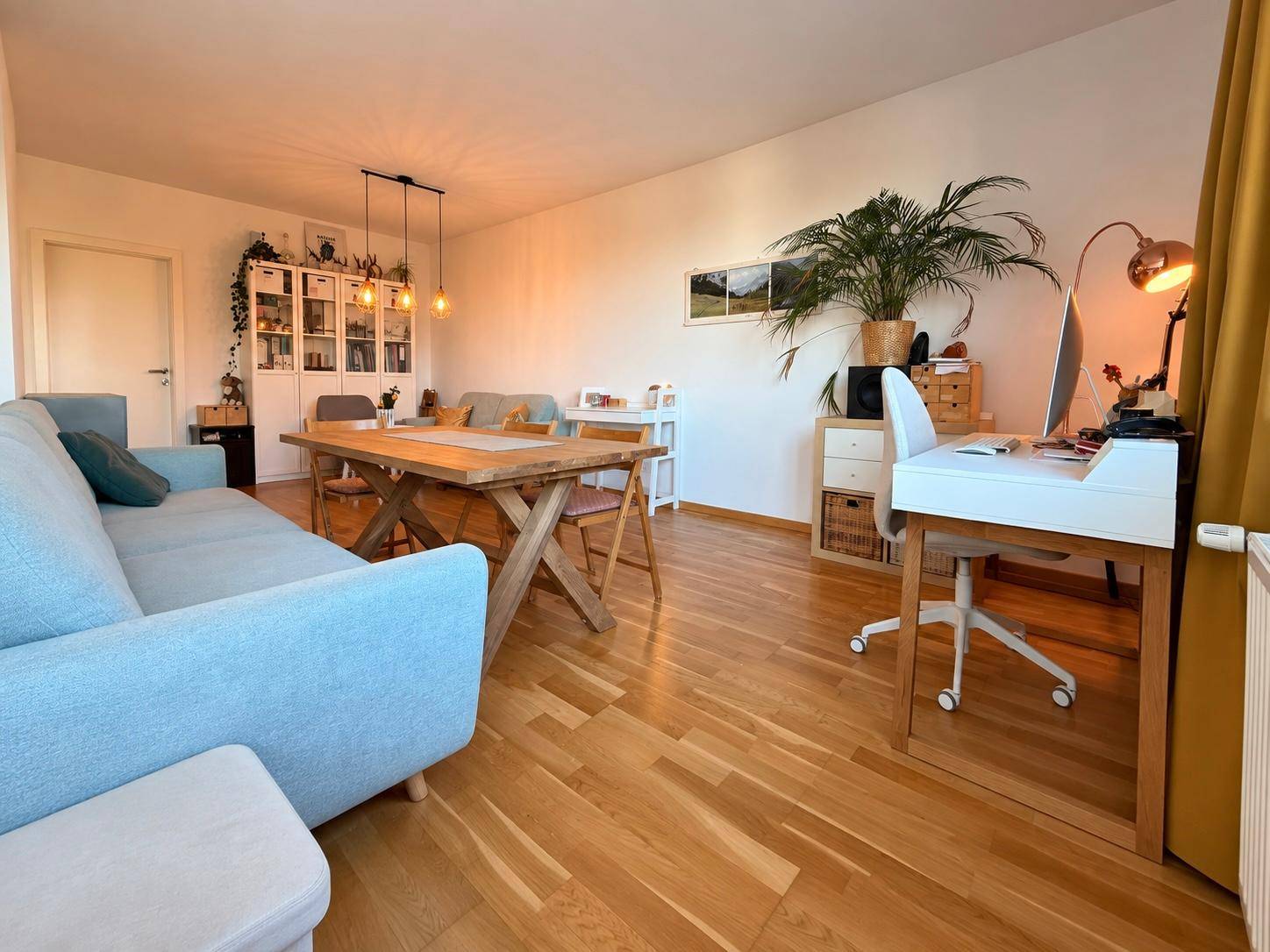 Geräumiger Wohn- und Essbereich mit Holztisch, Parkettboden und integriertem Arbeitsplatz.