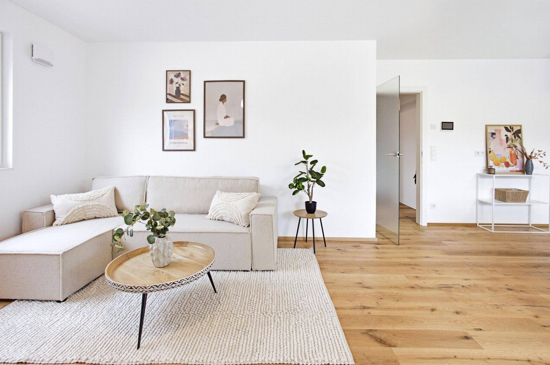 Gemütliches Wohnzimmer mit hellem Sofa, Holzboden und moderner Dekoration.