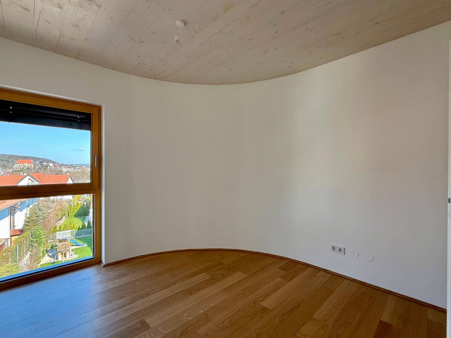 Helles Schlafzimmer mit Holzboden, großen Fenstern und Blick auf die Umgebung und Gärten.