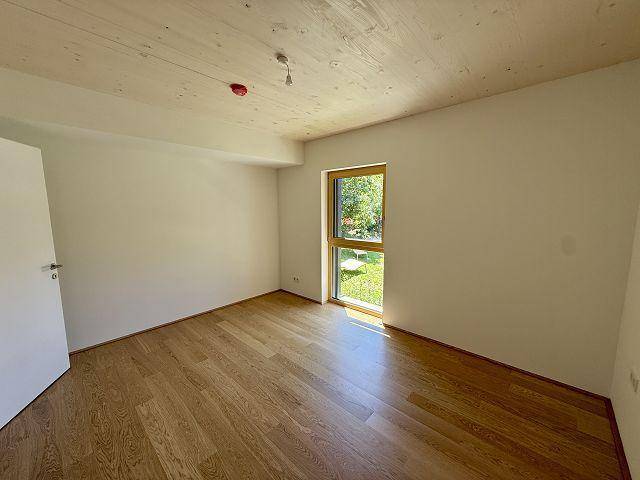 Modernes Schlafzimmer mit Holzboden und Fenster, das eine angenehme Atmosphäre schafft und viel Licht bietet.