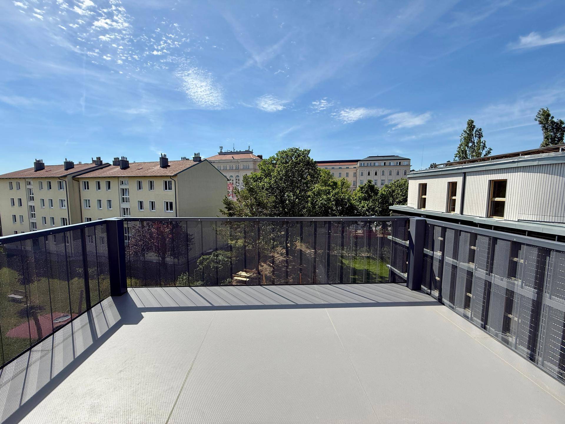 Sonniger Balkon mit Weitblick über die Stadt und angrenzende Gebäude.