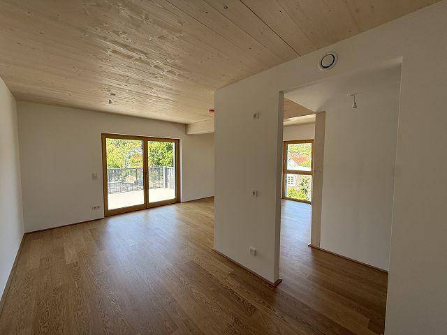 Großzügiger Raum mit Holzboden und Holzdecke, der viel natürliches Licht durch die Fenster erhält.