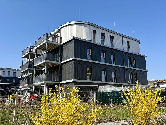 Moderne Architektur eines Neubaus mit dunkler Fassade und Balkonen in einer Wohnsiedlung.