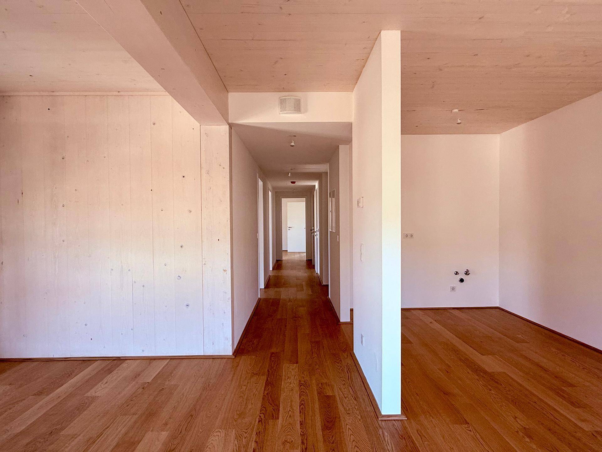 Langer Flur mit Holzboden und Zugang zu verschiedenen Räumen der Wohnung in modernem Stil.