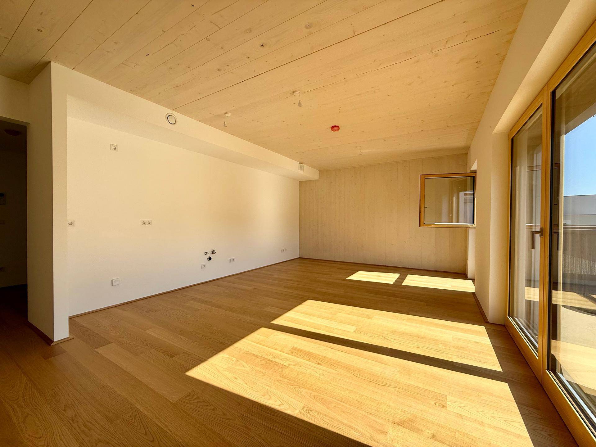 Geräumiger Wohnbereich mit Holzboden und viel Tageslicht, ideal für individuelle Gestaltung.
