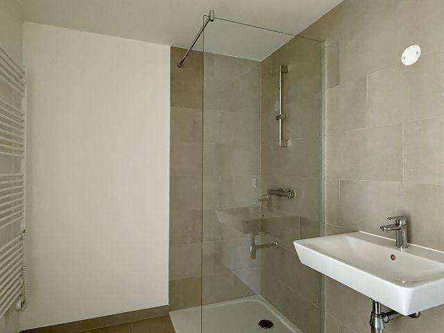 Helles Badezimmer mit moderner Dusche, Waschbecken und Handtuchheizkörper.