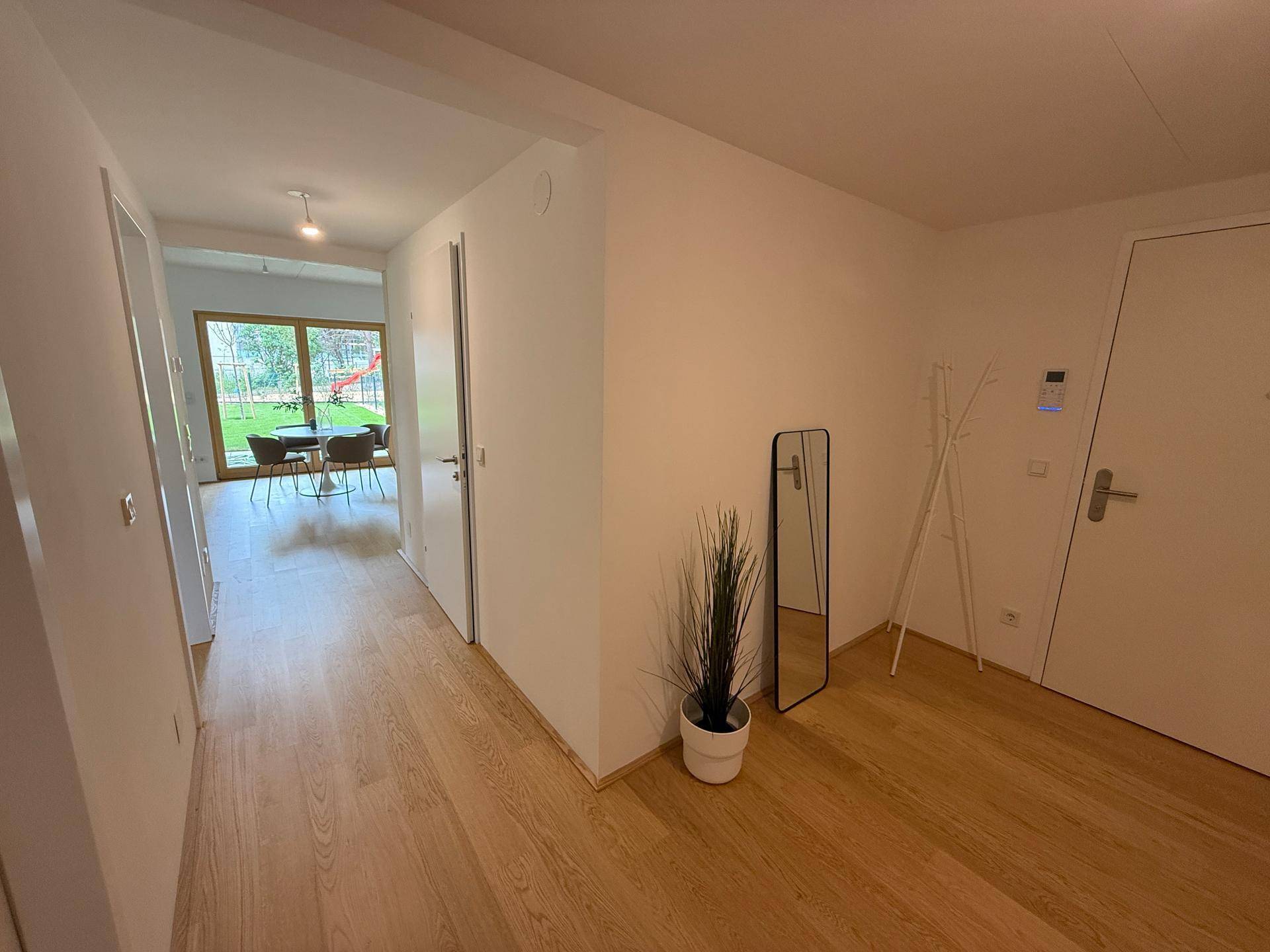 Heller Flur mit Holzboden, der zu den Wohnbereichen und dem Garten führt.