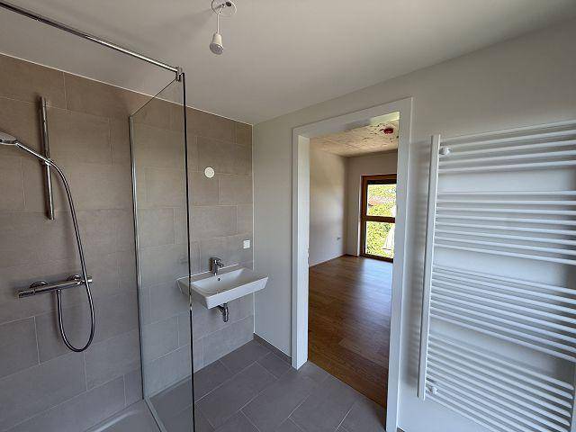 Modernes Badezimmer mit begehbarer Dusche, Fliesenboden und Handtuchheizkörper.