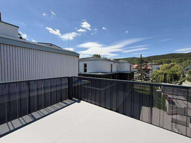Weitläufige Dachterrasse mit Blick auf die umliegenden Gebäude und die grüne Landschaft.