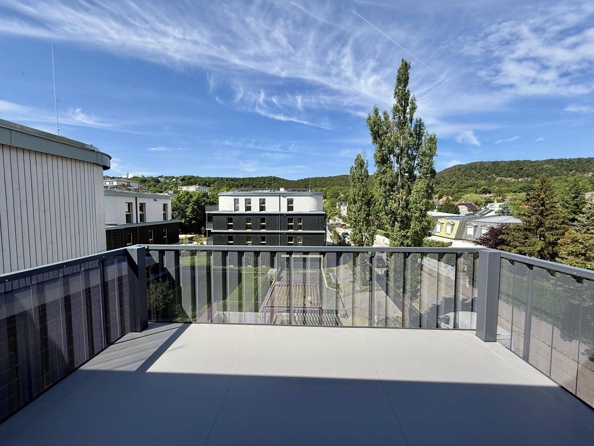 Geräumiger Balkon mit modernem Design und Ausblick auf die umliegende Bebauung und Natur.