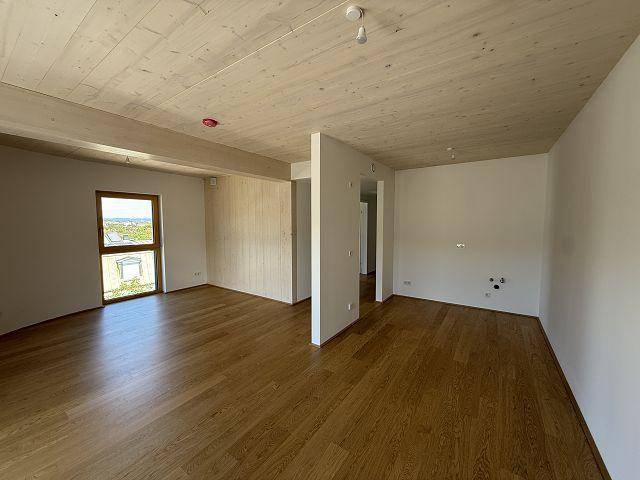 Heller, unmöblierter Raum mit Holzboden und Holzdecke, bereit für individuelle Gestaltung.