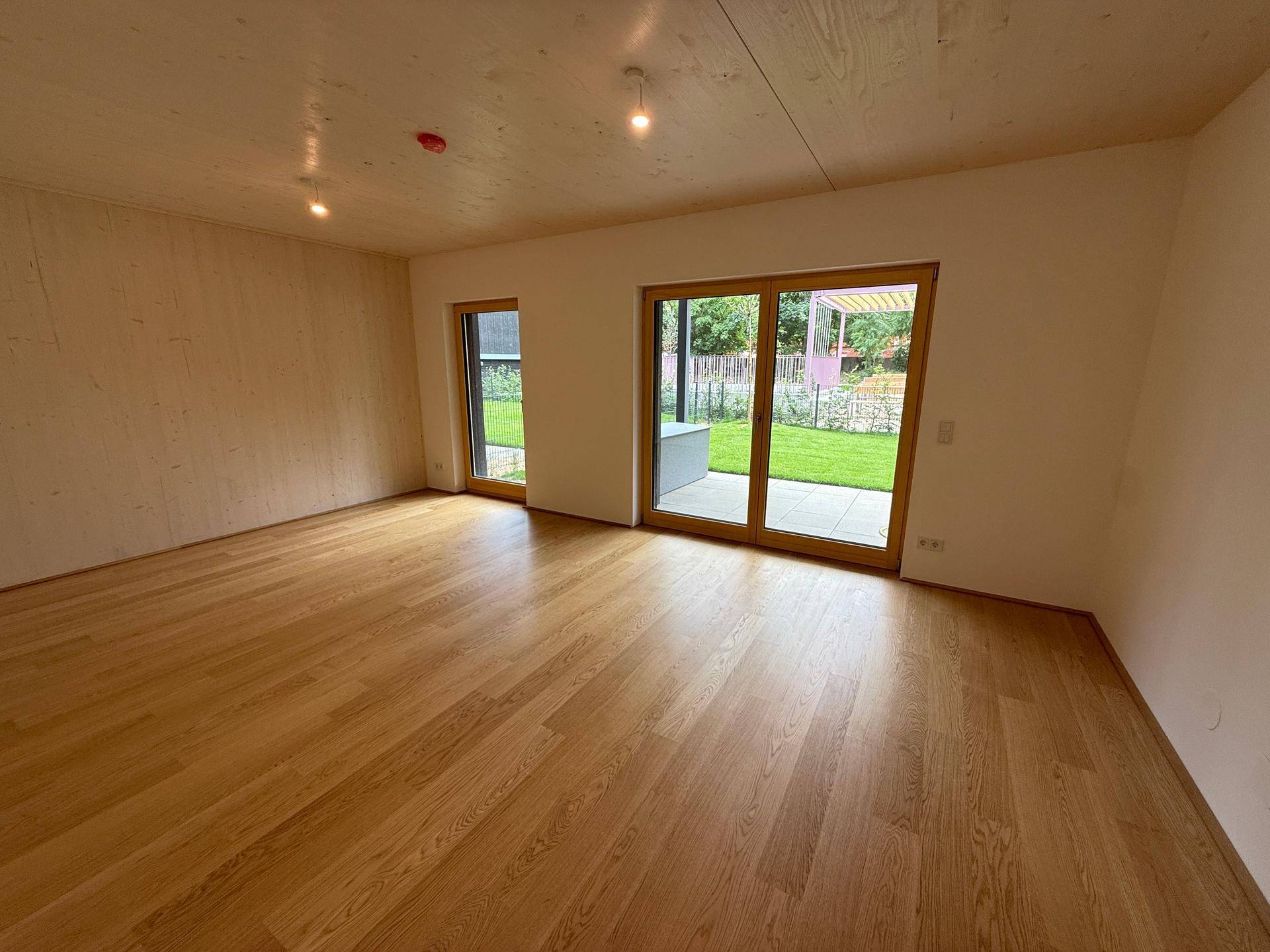 Geräumiges Zimmer mit hellem Eichenparkett und großen Fenstern zum privaten Gartenbereich.