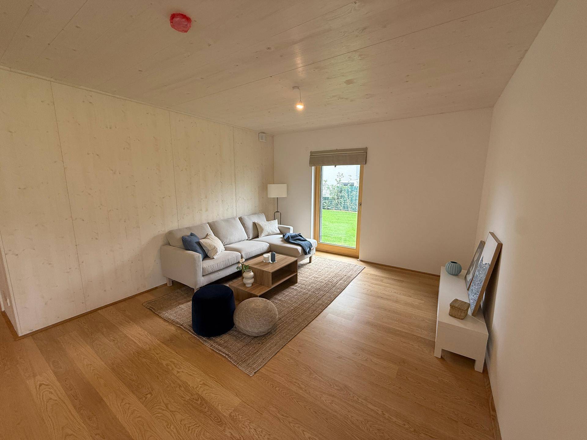 Gemütliches Wohnzimmer mit Sofa, Holzboden und direktem Zugang zum privaten Garten.