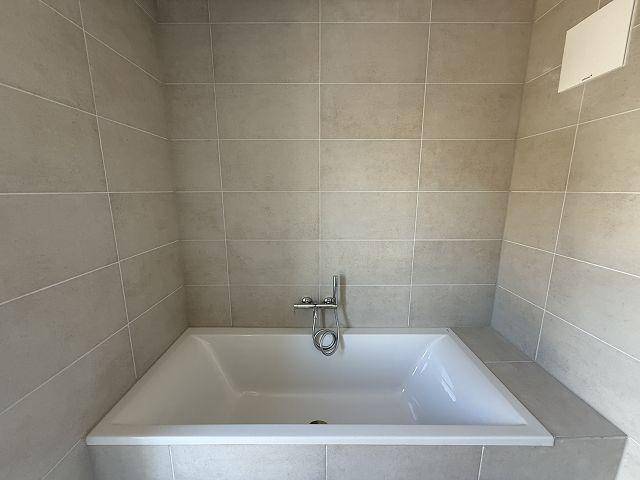 Eingebaute Badewanne in einem modern gefliesten Badezimmer, ideal zum Entspannen nach einem langen Tag.