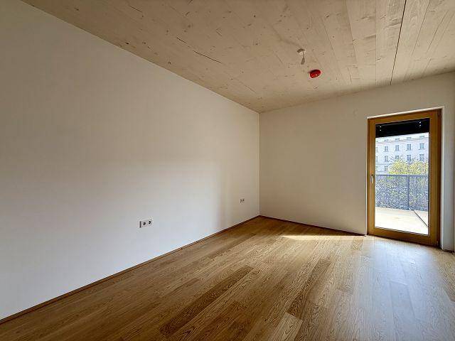 Helles Schlafzimmer mit Holzboden und Zugang zu einem Balkon, ideal für Ruhe.