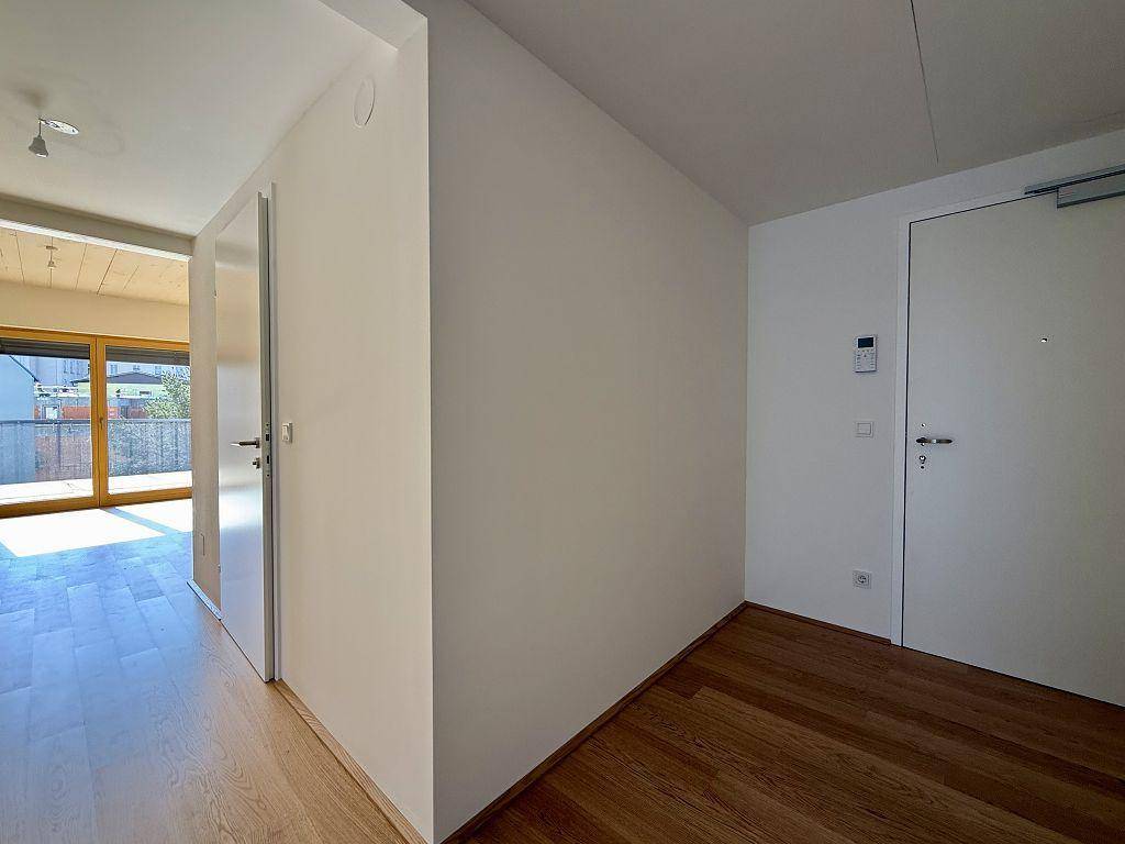 Heller Eingangsbereich mit Holzboden und Zugang zu den Wohnräumen sowie einem Balkon.
