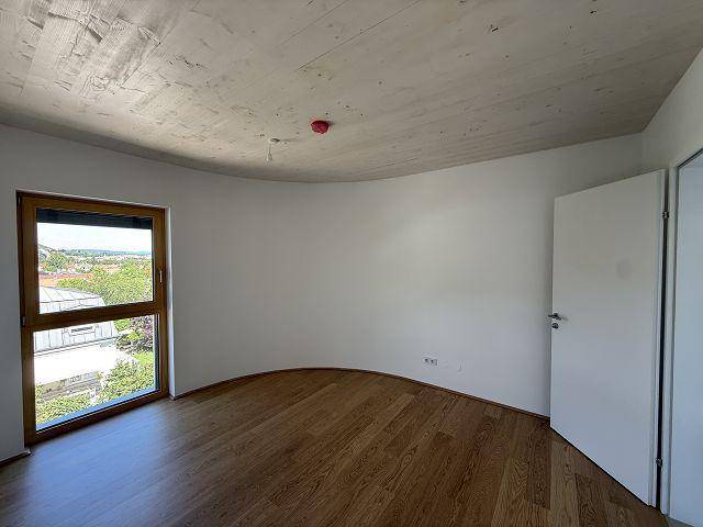 Helles Schlafzimmer mit Holzboden, Holzdecke und einem Fenster, das einen weiten Blick bietet.