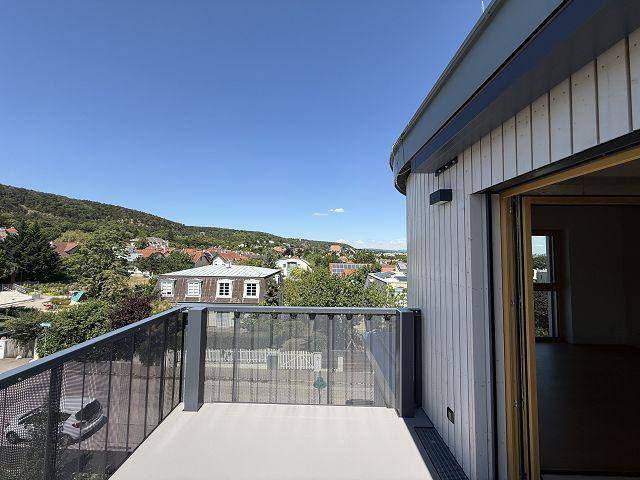 Sonnige Terrasse mit moderner Brüstung und weitem Blick auf die grüne Hügellandschaft.
